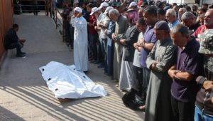 Mourners pray next to the body of one of two Palestinians killed by Israeli fire in Khan Younis in the southern Gaza Strip