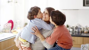 A mom hugging her sons in the kitchen