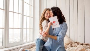 mother-hugging-cute-daughter-with-greeting-card_23-2148092265