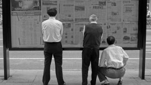 people_reading_newspaper_on_the_street